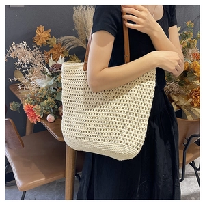 Detail showing the cream woven texture and brown leather strap on the large tote bag