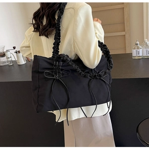 Detail van zwarte nylon draagtas met geplooide handvatten en strikken met contraststiksels