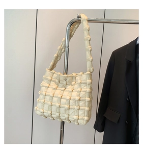 Close-up of beige quilted bubble shoulder bag with soft textured grid pattern detail