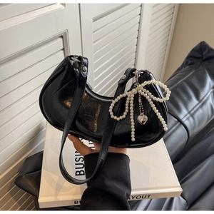 Detail of black crinkled leather crescent bag with pearl bow and heart pendant