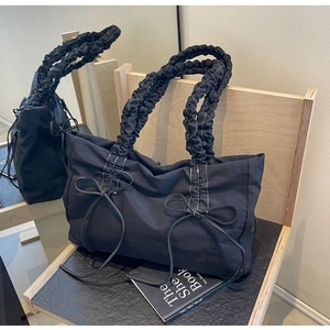 Detail van zwarte nylon draagtas met strikjes en contrastrerende witte stiksels