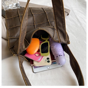 Spacious interior of dark brown leather tote bag showing items for daily commuting