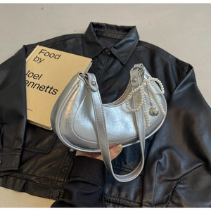 Detail of silver hobo bag with pearl bow charm on black leather jacket background