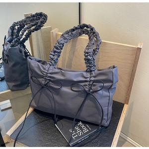 Detail van donkergrijze nylon tas met gerimpelde handvatten en zwarte strikaccenten
