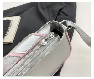 Detail of silver heart-shaped zipper puller on a stylish pink and silver shoulder bag