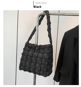 Detail of black puffer tote bag with padded quilted grid texture and wide shoulder strap