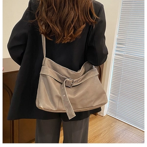 Detail of taupe leather hobo bag showing soft texture and silver buckle on model