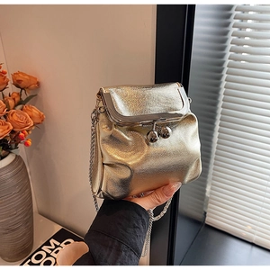Détail d'un sac bandoulière métallisé doré de luxe avec fermoir cliquet et chaîne
