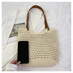 Detail of hollow woven tote bag with brown leather handle and phone for size comparison