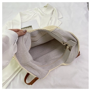 Detail view of large woven tote bag featuring inner zip pocket and leather handles