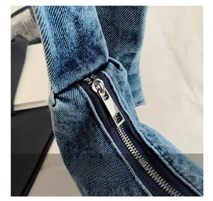Detail van de gladde zilveren metalen rits en blauwe denim textuur op de schoudertas