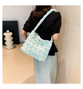 Macro shot of mint green puffed woven shoulder bag with 3D grid texture on a model