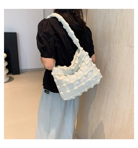 Detailed texture of a white quilted puffer hobo bag shown on a model's shoulder