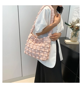 Close-up of pink puffy hobo bag with woven texture worn by model in a white suit