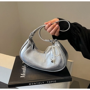 Detail of silver metallic hobo bag featuring pleated texture and pearl bow charm accessory