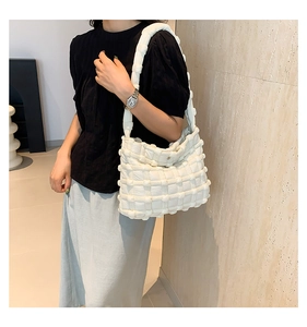 Detailed view of white quilted bubble shoulder bag with embossed texture on female model