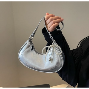 Detail of silver crescent bag with metallic cracked texture and pearl bow charm