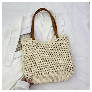 Detail of hollow woven tote bag with brown leather handles and metal rivet fasteners