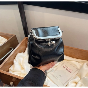 Dettaglio mini borsa in pelle lucida nera con chiusura a scatto e tracolla a catena