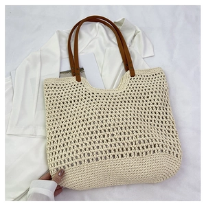 Detail of hollow mesh cotton woven tote bag with brown leather handles and rivets