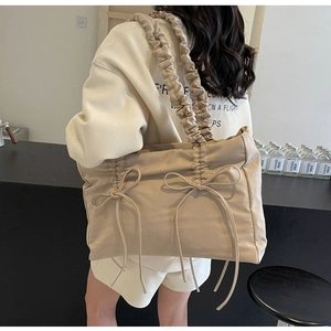 Detailweergave van beige nylon draagtas met ruches schouderband en strikaccenten