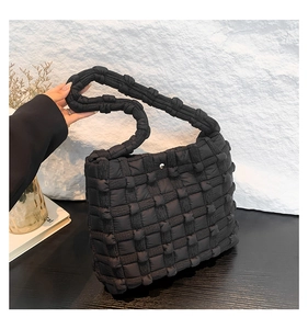 Detail of black puffer woven shoulder bag with thick quilted padding and texture