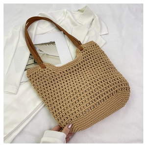 Detail of hollow woven tote bag with brown leather handles on a summer holiday background