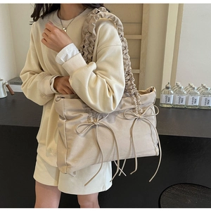 Detail van beige nylon schoudertas met geplooid handvat en fijne strikjes als accent