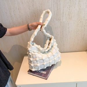 Detail showing white quilted puff fabric and woven texture of the large shoulder bag