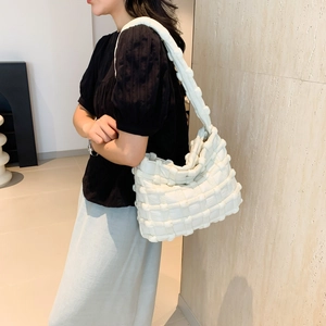 Detail shot of a white woven puffy shoulder bag showing the unique soft braided texture