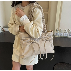 Detail van beige geplooide schoudertas met lintstrikken en minimalistische zachte stoftextuur