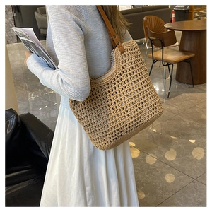 Detail of hollow woven tote bag featuring brown leather straps and metal rivets