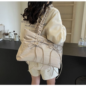 Detail van beige nylon schoudertas met grote strik en geplooide band op casual model
