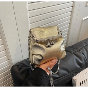 Détail du sac bandoulière doré avec fermoir à baiser et finition nacrée