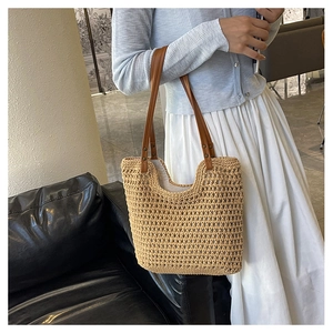 Detail of woven cotton beach tote bag featuring brown leather straps and metal rivets
