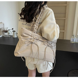 Detail van beige shopper met geplooide trekkoordsluiting en decoratieve strikken voor dames