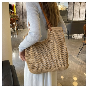 Detail of hollow woven shoulder bag with brown leather straps and vintage rivets