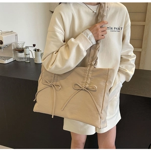 Detail van beige draagtas met strikaccenten en een geplooide schouderband ontwerp