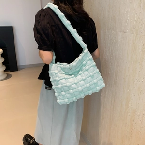Detail of mint green woven puff shoulder bag with textured fabric and metal buckle