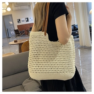Detail of hand-woven cotton tote bag with brown leather handles and metal rivets