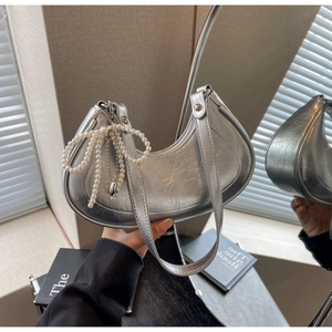 Detail of silver crescent shoulder bag with pearl bow and heart charm on metallic leather
