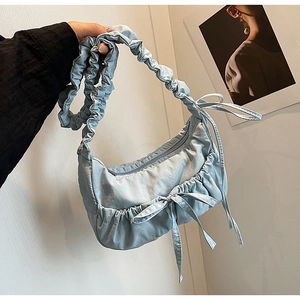 Detail of ruched shoulder bag in light blue with bow accents and zip closure