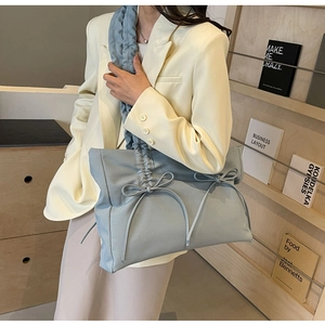 Detail van lichtblauwe nylon tas met decoratieve strikken en gerimpelde schouderband