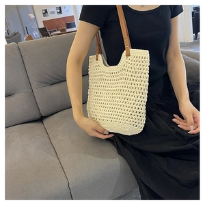 Detail of hollow woven tote bag with beige cotton mesh and brown leather straps