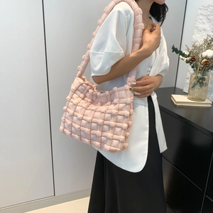 Detail of light pink woven puff shoulder bag showing the soft quilted texture and wide strap
