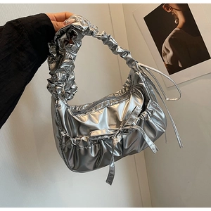 Detail of silver metallic pleated hobo bag featuring bow drawstring and cloud handle