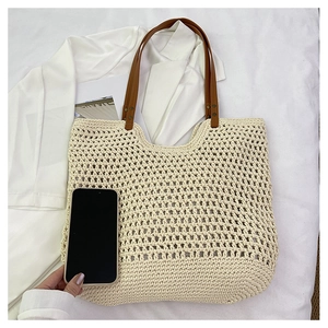 Detail of hollow woven cotton tote bag with leather handles and smartphone for scale