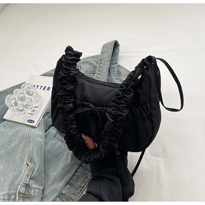 Detail of a black pleated nylon saddle bag placed on a denim jacket in a lifestyle setting