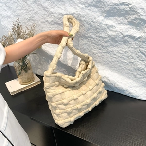 Close-up of cream white puff shoulder bag with woven texture and knotted strap detail