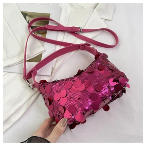 Detail of magenta sequin handbag featuring a long adjustable strap and silver metal buckle